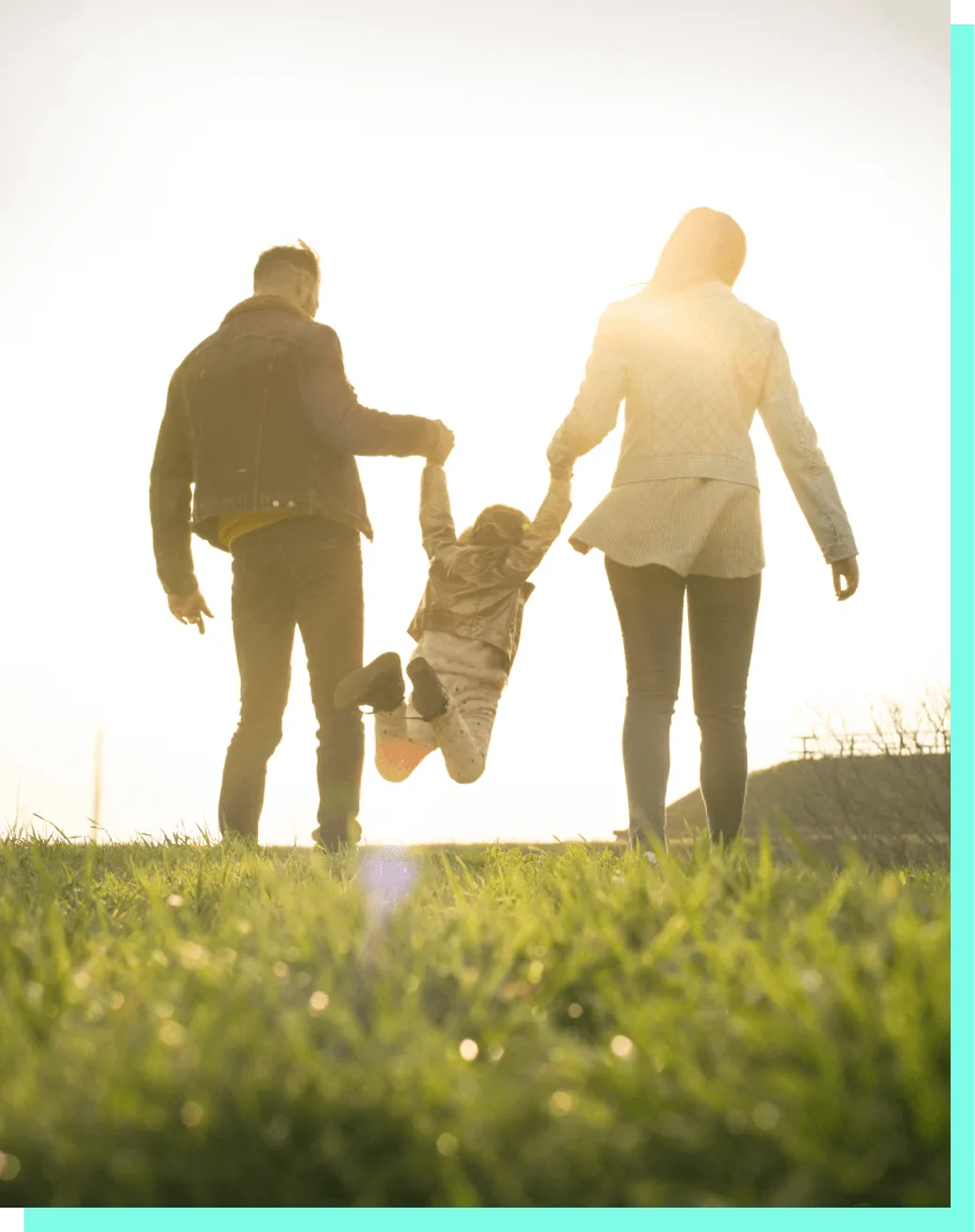 Family walking through a field at sunset